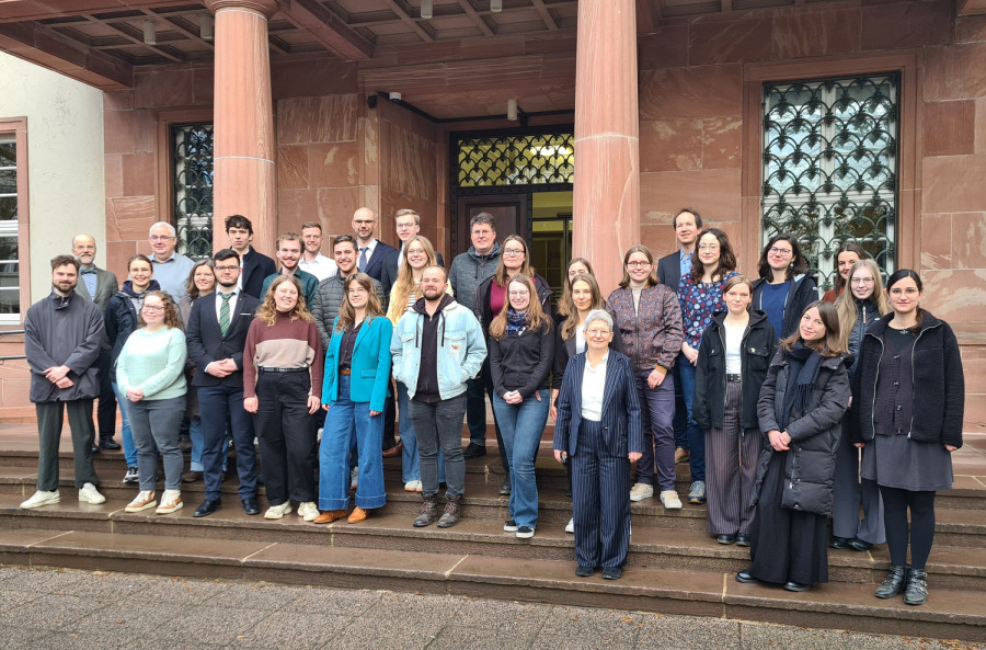 Eine Gruppe Menschen steht auf den Stufen vor einem Gebäude mit Säulen.